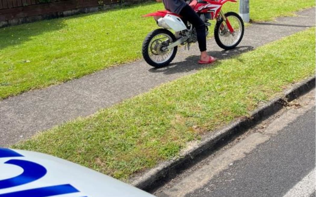 A dirt bike in a public space with a police vehicle nearby