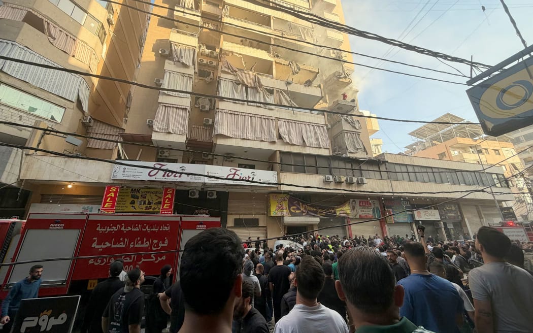 People gather looking at a residential building following an Israeli military strike in Beirut's southern suburbs.