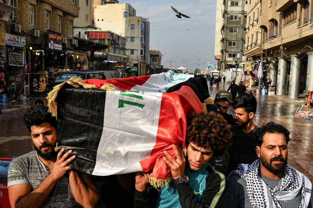 Iraqi mourners carry a coffin, draped in a national flag, of a tuktuk driver who ferried injured protesters and who was later killed in Baghdad.