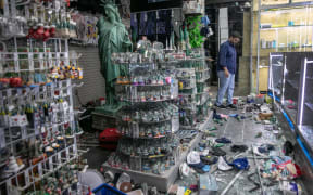 A shop owner looks over damage in a looted souvenir shop near Times Square a