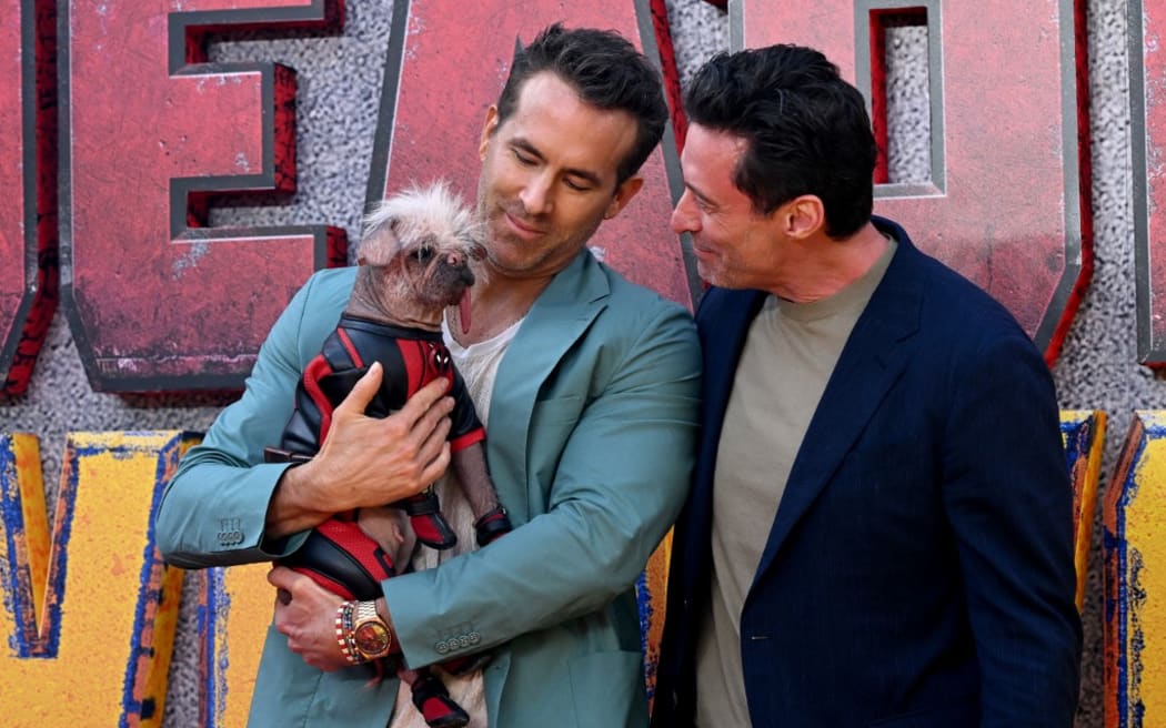 Canadian-US actor Ryan Reynolds (L) and Australian actor Hugh Jackman pose with UK’s Ugliest Dog Winner Dogpool on the red carpet upon arrival to attend the UK sneak peek event for 