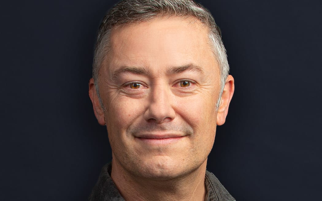 Nick Tipping looks down the camera wearing a grey shirt.