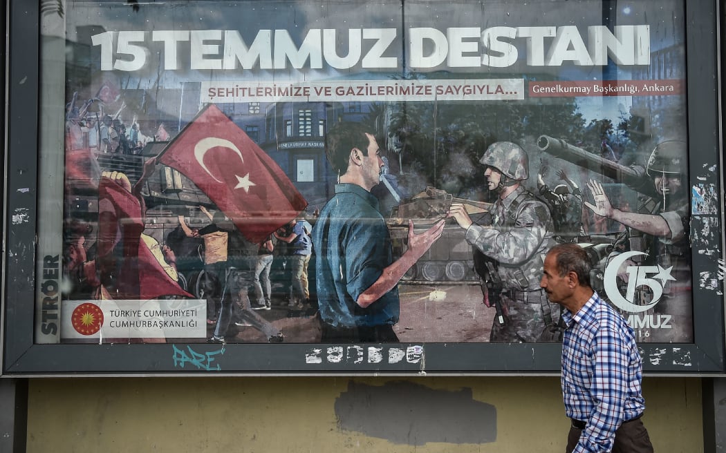A man walks past a giant billboard reading "Legend of July 15" for the anniversary of the last year's attempted coup in Turkey
