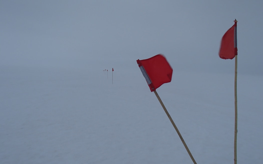 Small flags mark the safe route to walk during a white-out on the sea ice in front of Scott base, Antarctica.