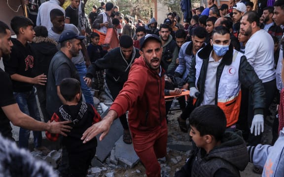 A Palestinian medic and civilians carry an injured man after an Israeli strike on Rafah, in the southern Gaza Strip on November 23, 2023, amid continuing battles between Israel and the Palestinian militant group Hamas. (Photo by SAID KHATIB / AFP)