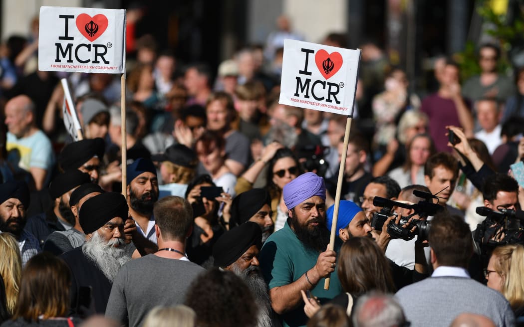 Members of Manchester's Sikh community carry "I love MCR" banners as they arrive to attend the vigil following the attack at Manchester Arena.