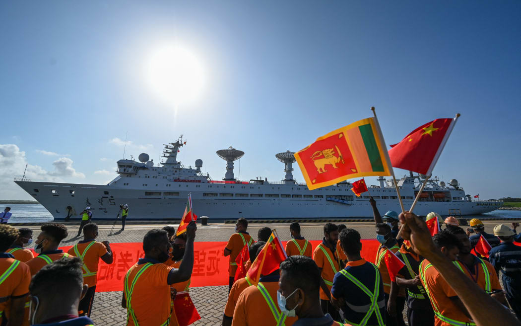 Workers wave China's and Sri Lanka's national flags upon the arrival of China's research and survey vessel, the Yuan Wang 5 at Hambantota port, Sri Lanka on 16 August, 2022.