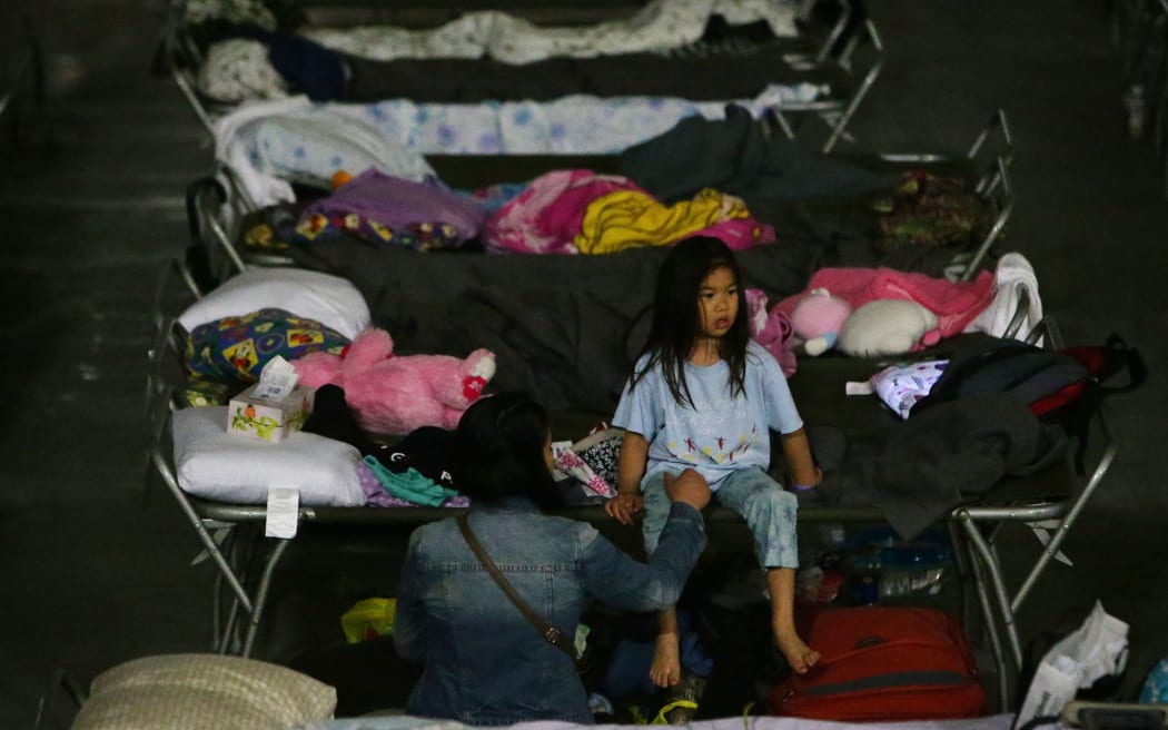 A young girl sits on a cot at a makeshift evacuee center in Lac la Biche, Alberta, 5 May, after fleeing forest fires north of Fort McMurray.