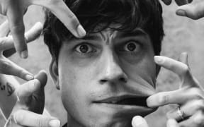 Choreographer Corey Baker with hands around his face mimicking 'Thing' from the TV show Wednesday.