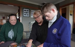 Ryan, with carer Trishna Williams, left, and mum Pip Cook, centre.