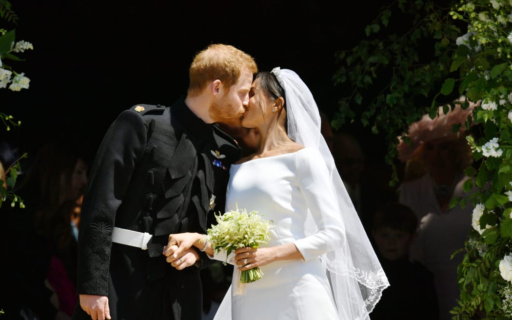 Britain's Prince Harry, Duke of Sussex kisses his wife Meghan, Duchess of Sussex as they leave from the West Door of St George's Chapel, Windsor Castle, in Windsor, on May 19, 2018 after their wedding ceremony. / AFP PHOTO / POOL / Ben Birchall