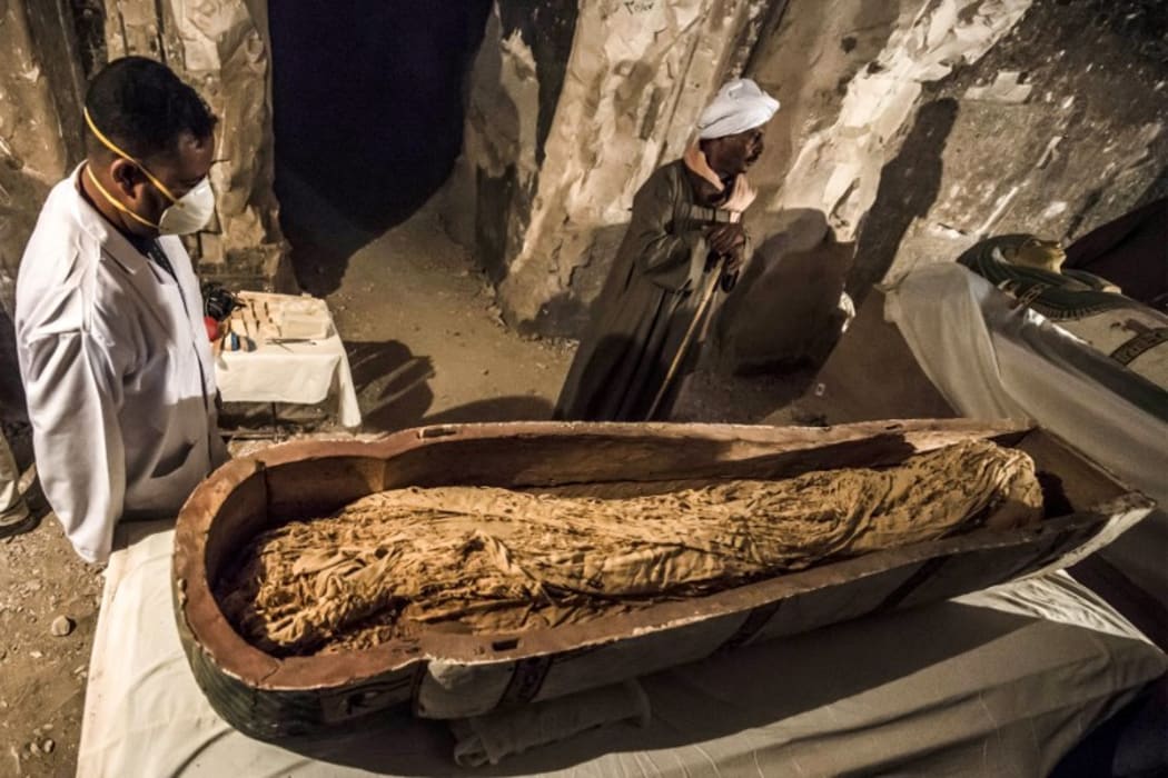 November 24, 2018: Egyptian workers and archaeologists standing next to an opened intact sarcophagus containing a well-preserved mummy of a woman named "Thuya", discovered at Al-Assasif necropolis in Luxor, Egypt
