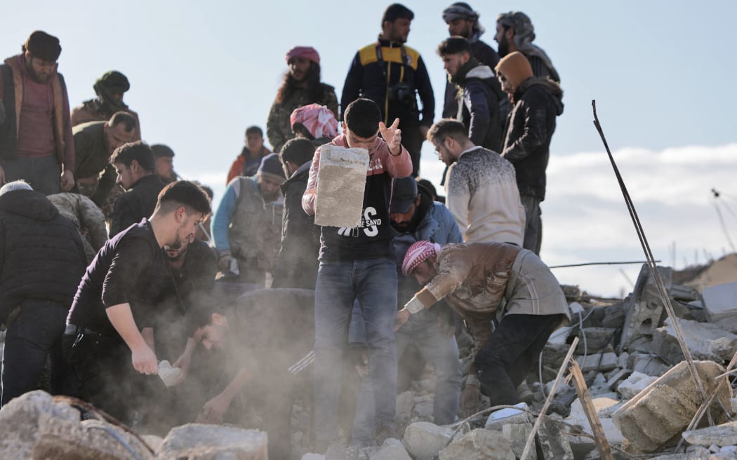 EDITORS NOTE: Graphic content / Syrian rescuers and civilians shift through the rubble of a collapsed building on February 7, 2023, in the town of Jandairis, in the rebel-held part of Aleppo province, as search and rescue operations continue following a deadly earthquake. - The death toll from the massive earthquake that struck Turkey and Syria rose above 8,300, official data showed, with rescue workers still searching for trapped survivors. (Photo by Bakr ALKASEM / AFP)