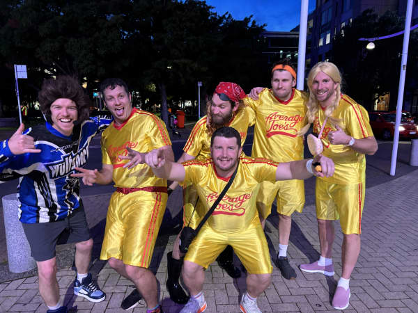 A group of smiling men in shiny yellow two-piece outfits.