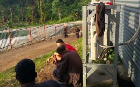 Refugees watch the action unfolding at the gate of Hillside Haus.