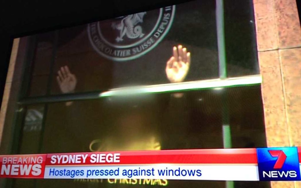 A hostage in the Sydney cafe with their hands on the window.