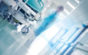 Medical bed in hospital hallway with professionals hurrying to the emergency case