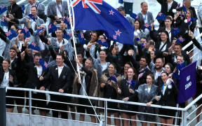 Flagbearers Aaron Gate and Jo Aleh are surrounded by New Zealand tea-mates aboard a barge sailing on the Seine River during the Paris Olympics opening ceremony.
