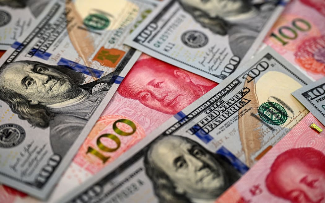 This photo illustration shows Chinese 100 yuan notes (red) and US 100 dollar notes, in Beijing on April 8, 2025. China vowed on April 8 to "fight to the end" against fresh tariffs of 50 percent threatened by US President Donald Trump, further aggravating a trade war that has already wiped trillions off global markets. (Photo by Jade GAO / AFP)
