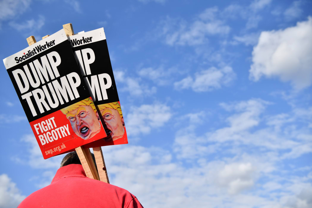 A demonstrator holds placards during a protest outside Buckingham Palace against US President Donald Trump's visit.