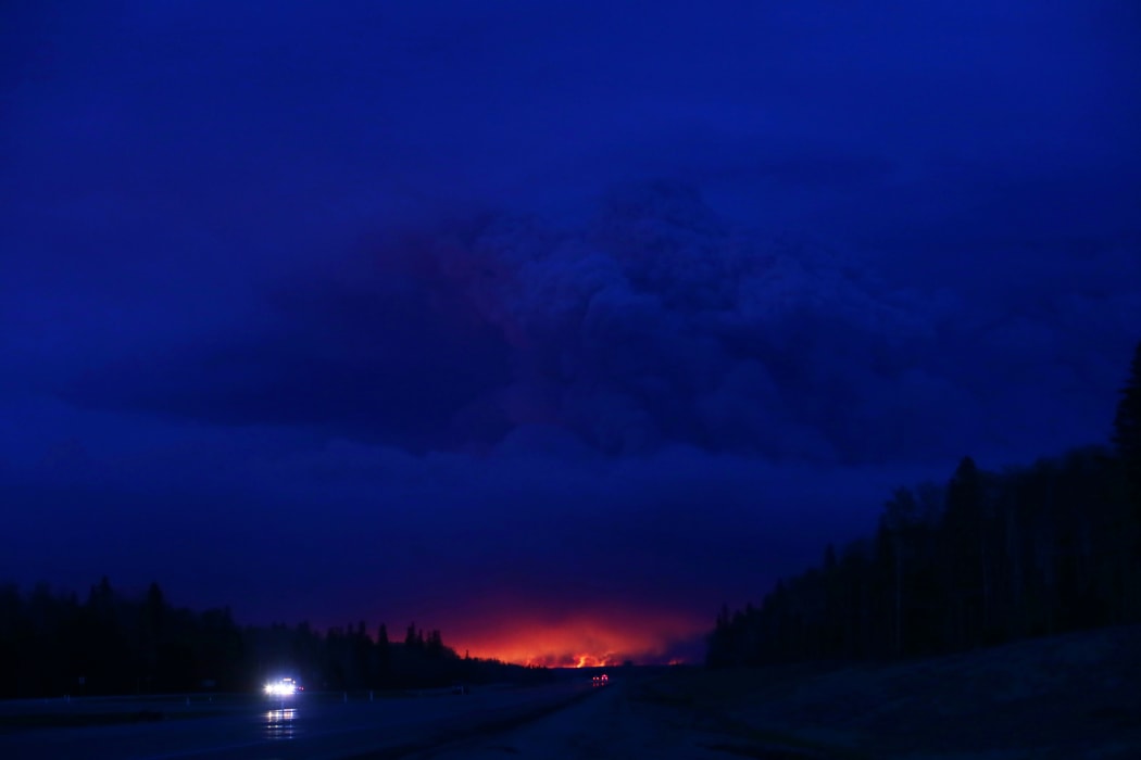 A plume of smoke hangs in the air as forest fires rage on in the distance in Fort McMurray.