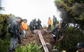 Volunteers help to carry the McKenzie Brothers Flag Pole down from Bluff Hill