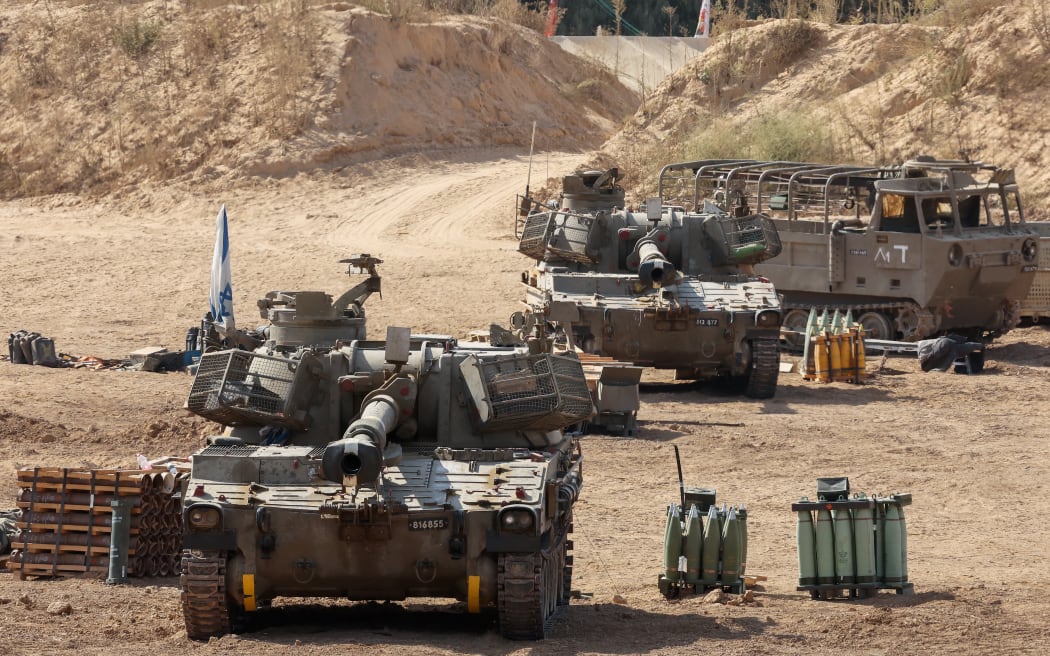 This picture taken from a position at Israel's border with the Gaza Strip shows Israeli mobile artillery units deployed near the border fence with the besieged Palestinian territory on September 17, 2025. Israel launched its ground assault on Gaza City before dawn on September 16, shortly after the US Secretary of State's visit expressing robust support for the offensive, while a United Nations probe charged Israel with committing "genocide" in the Palestinian territory and accused its Prime Minister and other top officials of incitement. (Photo by Jack GUEZ / AFP)