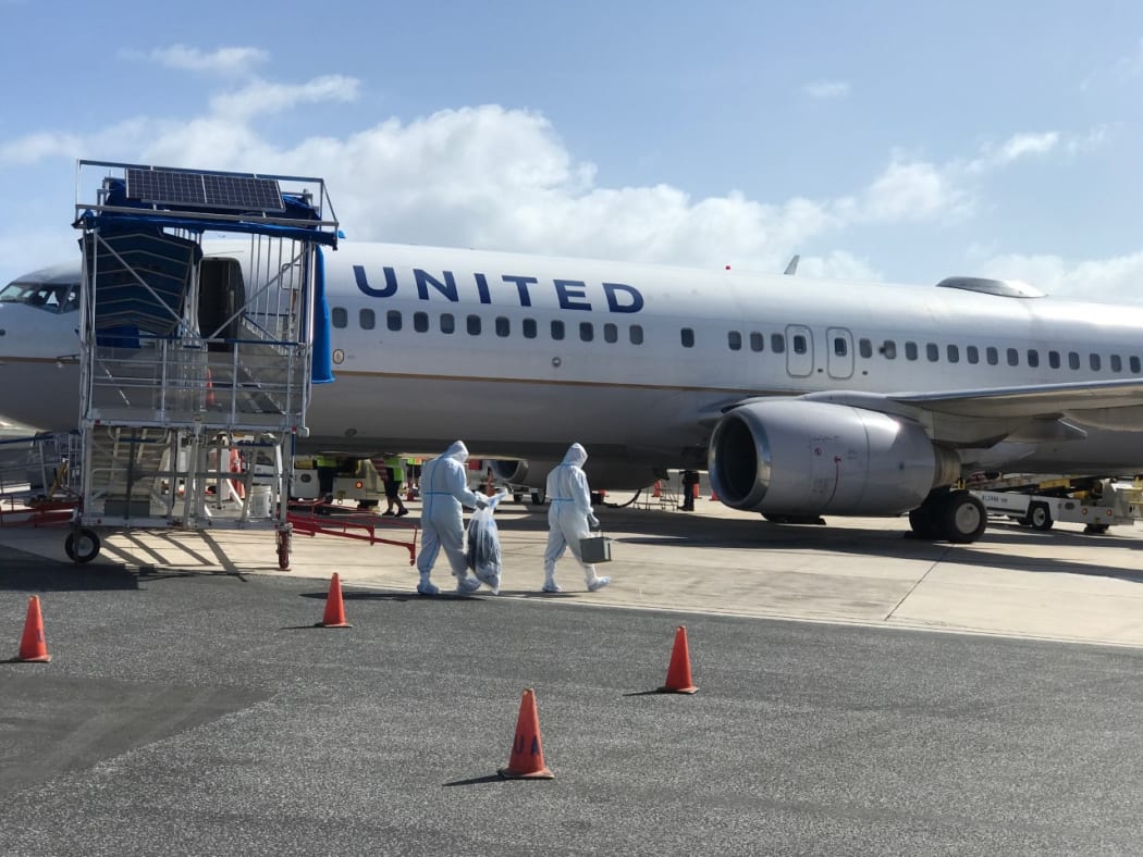 For the one flight per month now scheduled to the Marshall Islands, United Airlines Majuro workers don full-body personal protective gear to briefly enter the plane.