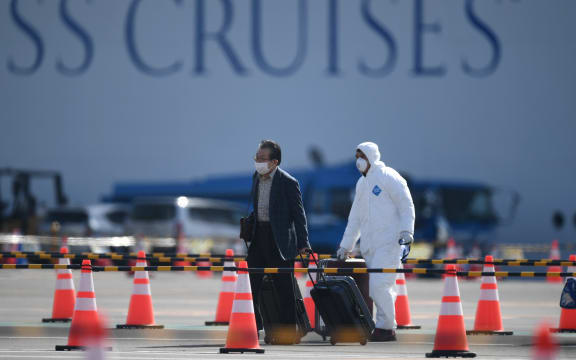A passenger, left, disembarks from the Diamond Princess at Yokohama on Wednesday 19 February 2020.
