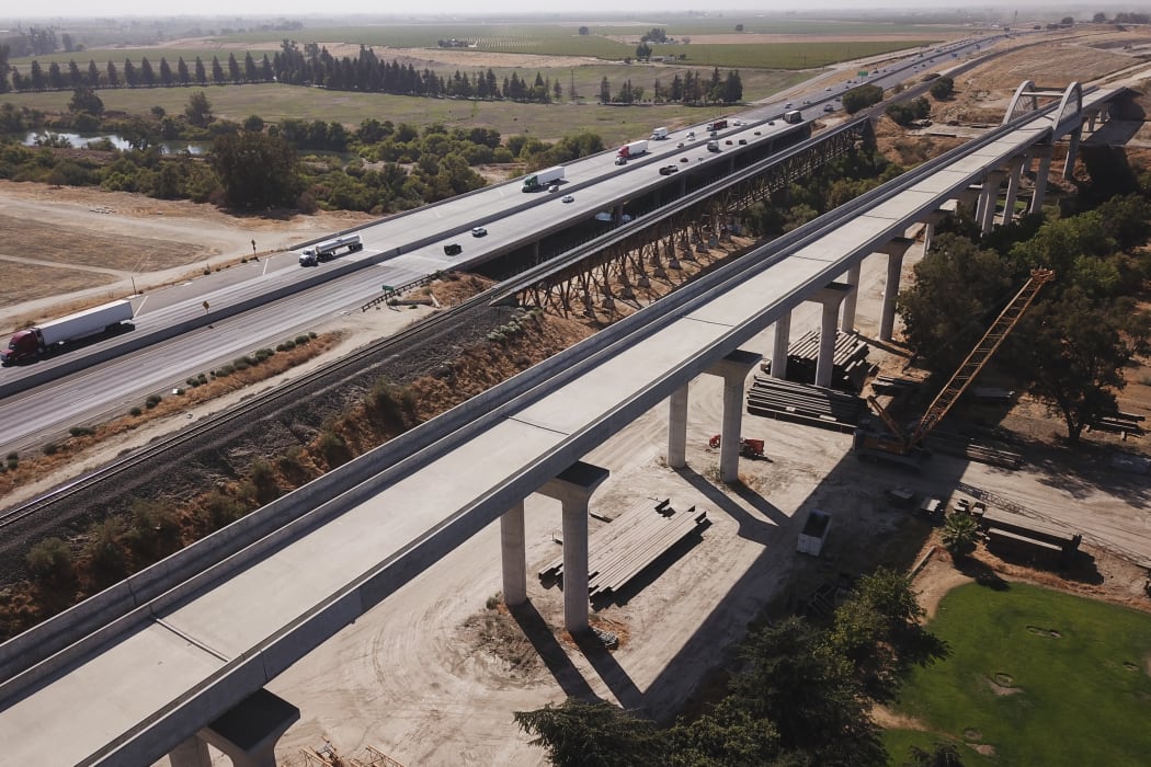 In this aerial image taken on August 26, 2021 vehicles drive past farmland and part of the California High Speed Rail Authority San Joaquin River viaduct construction project alongside US Highway 99 through the Central Valley between Madera County and Fresno County, California.
