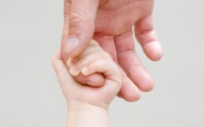 A close up of a child holding and adult's hand