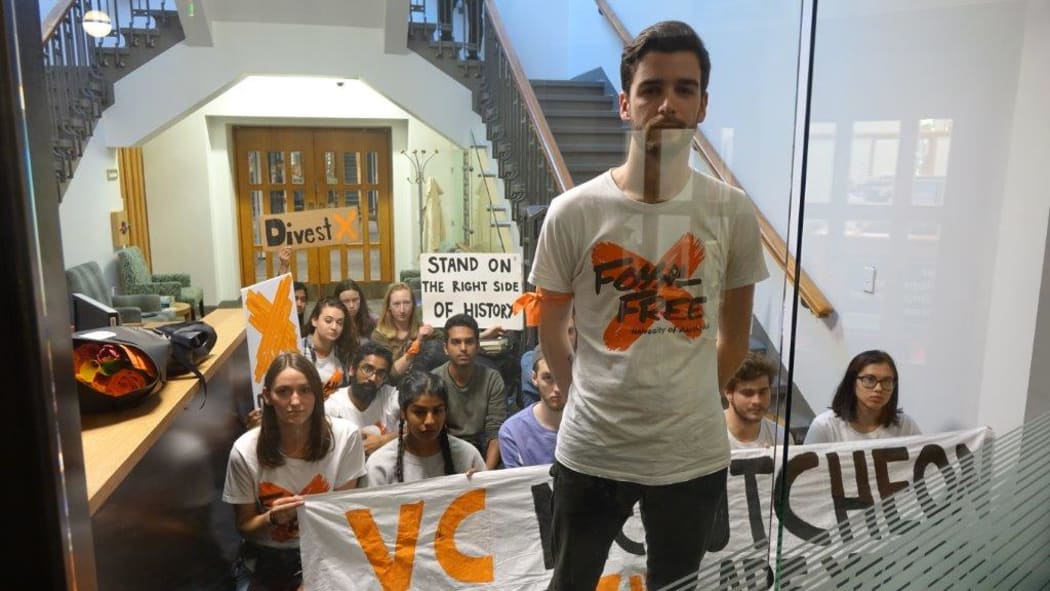 Alex Johnston, from Fossil Free University of Auckland, with other protesters locked in the Vice-Chancellor's reception area by campus security, after occupying a wing of the administration block.