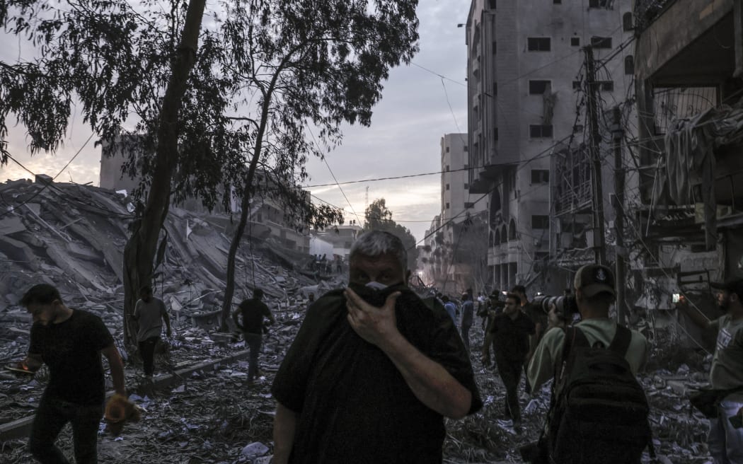 People walk atop the rubble of a tower destroyed in an Israeli air stike in Gaza City on October 7, 2023. Palestinian militants have begun a "war" against Israel which they infiltrated by air, sea and land from the blockaded Gaza Strip, Israeli officials said, a major escalation in the Israeli-Palestinian conflict.