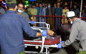 EDITORS NOTE: Graphic content / Volunteers and medical staff bring an injured man on a stretcher to a hospital for treatment after two powerful explosions, which killed at least six people, outside the airport in Kabul on August 26, 2021.