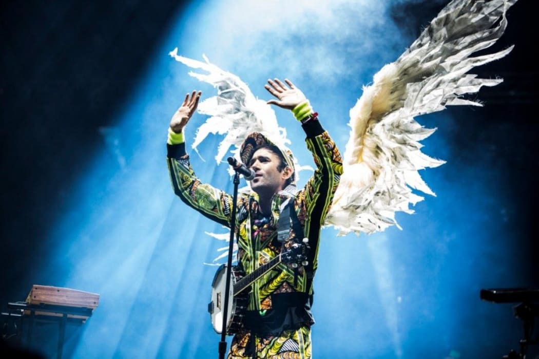 Sufjian Stevens performs on stage wearing large angel wings