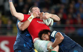 British and Irish Lions captain Ken Owens (C) is tackled by Blues' Alex Hodgman (L) and Steven Luatua (R) during the rugby match between The British and Irish Lions and Auckland Blues at Eden Park.