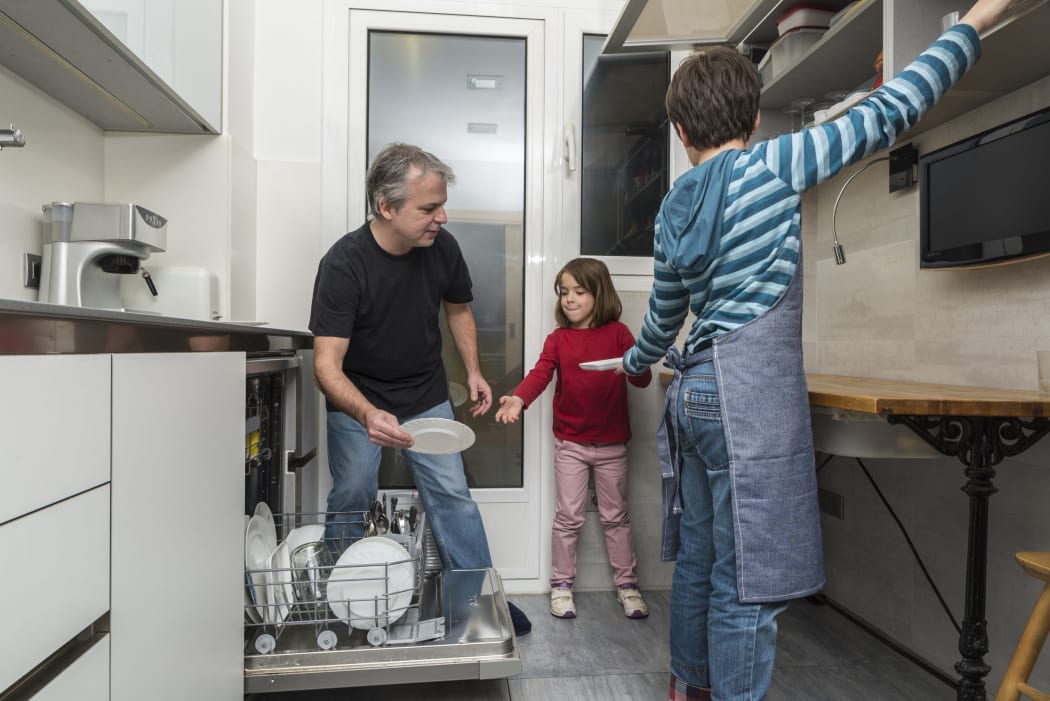 A photo of a father and sons together emptying the dishwasher