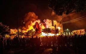 Protesters gather around a liquor store in flames near the also-burned Third Police Precinct in Minneapolis, in a third day of protests after the death of George Floyd.