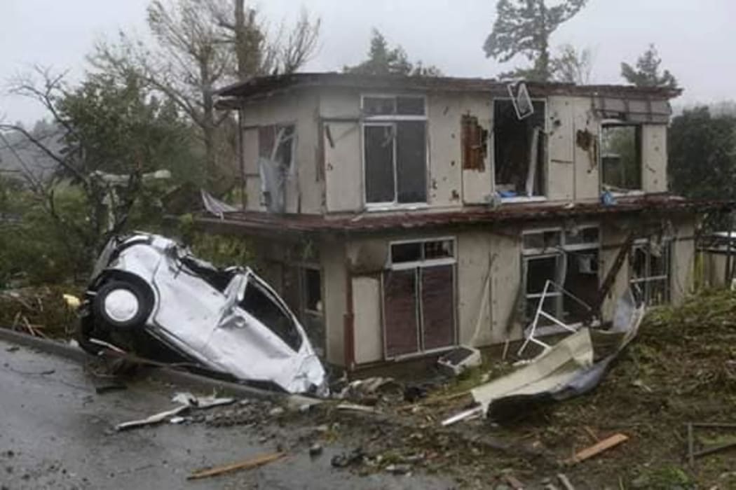 A car sits among debris near a damaged house in Chiba.