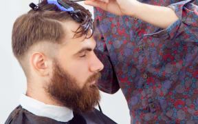 barber cutting hair with scissors and comb. side view of man in barber shop.