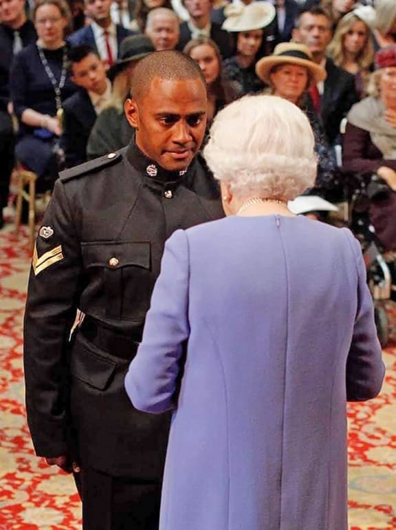Cpl Saimone Qasenivalu receiving his medal from Queen Elizabeth in London.