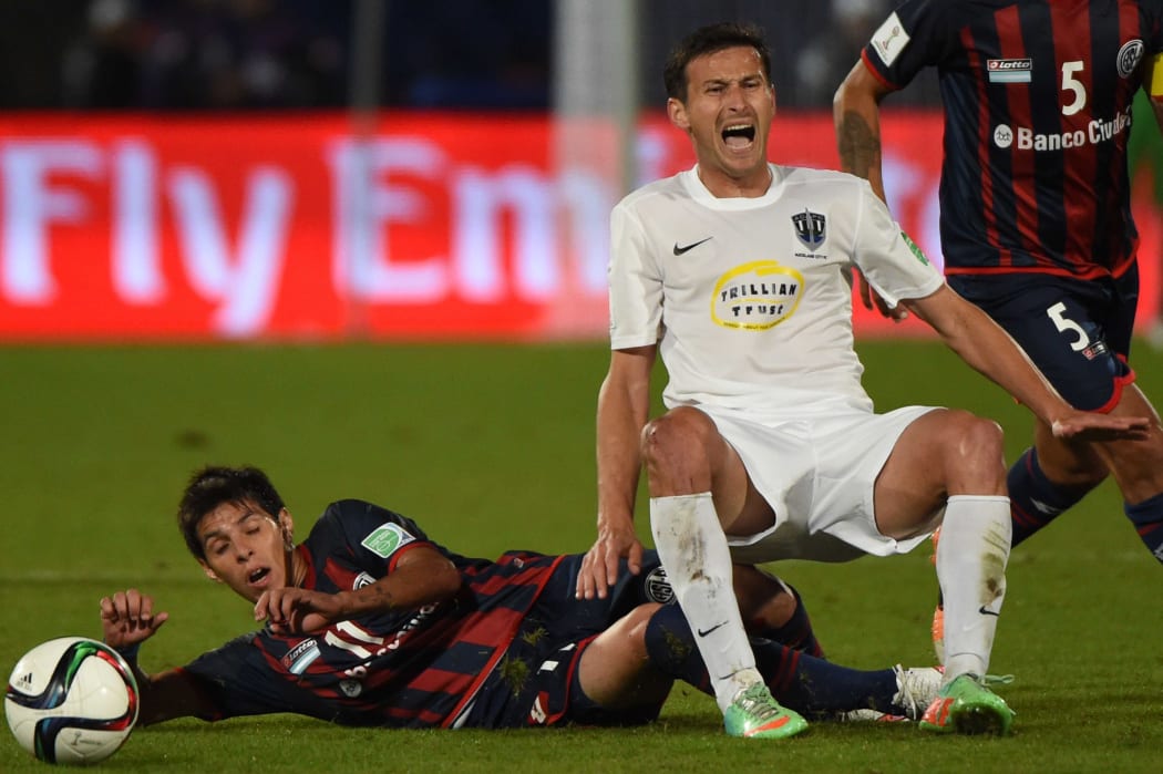 San Lorenzo's midfielder Pablo Barrientos (L) tackles Auckland City's foward Ryan De Vries (C) during the FIFA Club World Cup semifinal football match San Lorenzo vs Auckland City FC at the Marrakesh stadium in the Moroccan city of Marrakesh.
