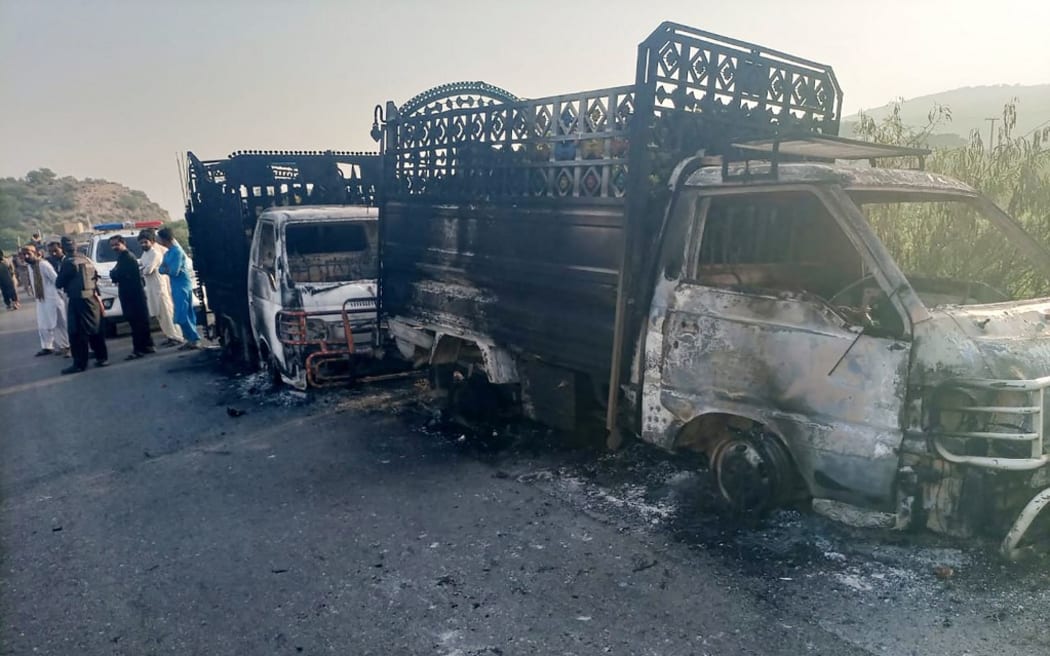 Security personnel stand near charred vehicles at the site of a shooting on a highway in Musakhail district, Balochistan province on 26 August 2024.