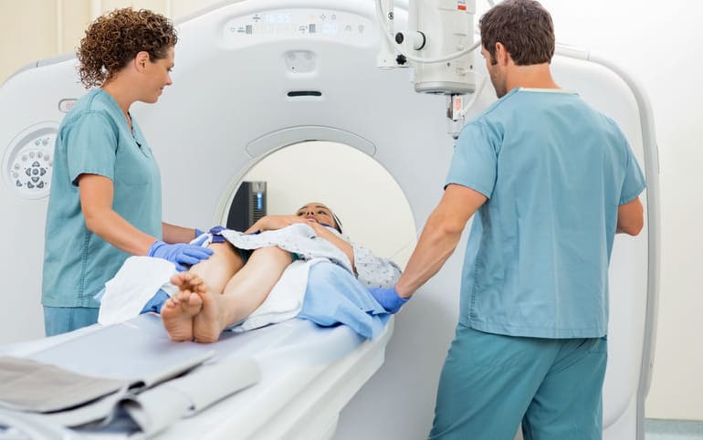A nurse prepares a woman for a CT scan.