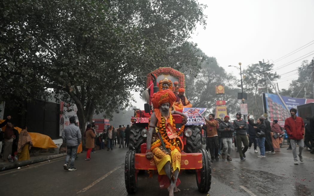 A Hindu sadhu sits in front of a tractor, during a religious procession in Maha Kumbh Mela in Prayagraj, Uttar Pradesh, India, 12 January, 2025. The millennia-old Kumbh Mela, a sacred show of religious piety and ritual bathing that opened on January 13, is held at the site where the holy Ganges, Yamuna and the mythical Saraswati rivers meet, bringing millions to celebrate spiritual rebirth and enlightenment. (Photo by Indranil Aditya / Middle East Images / Middle East Images via AFP)