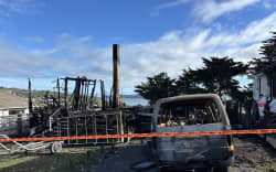 The aftermath of a fire in Spur Grove, Tītahi Bay, Porirua, on 21 June 2026, which badly damaged a house and a caravan on neighbouring properties the night before.