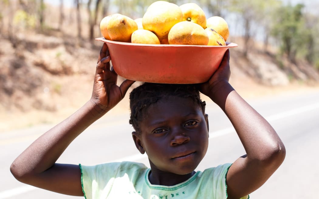 An African girl carrying a basket on her head. Zambia