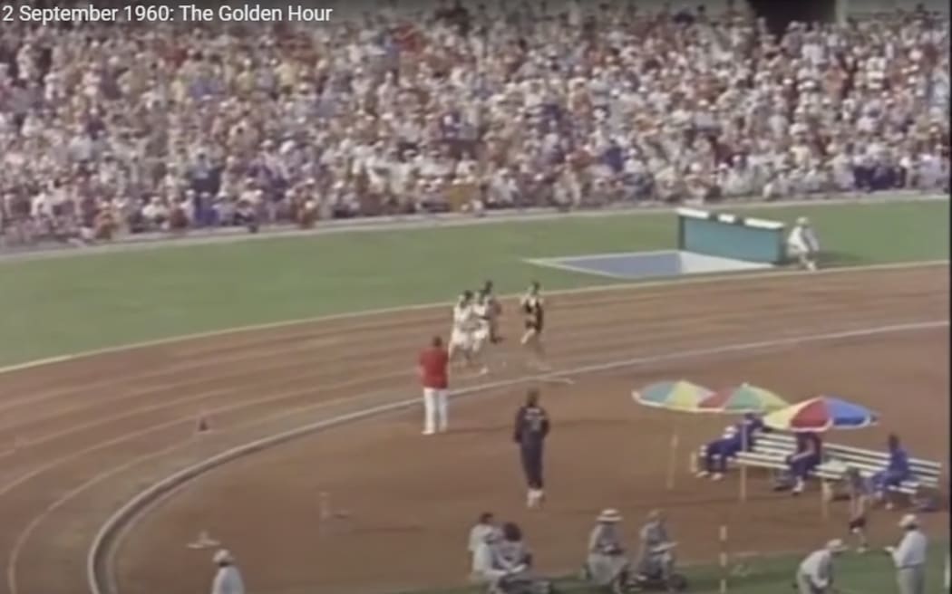 Val Young in centre field jumping up and down with excitement as Peter Snell rounds the bend ready for his push towards gold