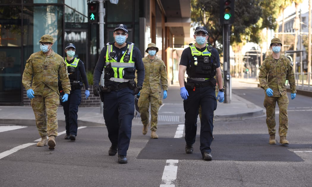 A group of police and soldiers patrol the Docklands area of Melbourne on August 2, 2020, after the announcement of new restrictions to curb the spread of the COVID-19 coronavirus.
