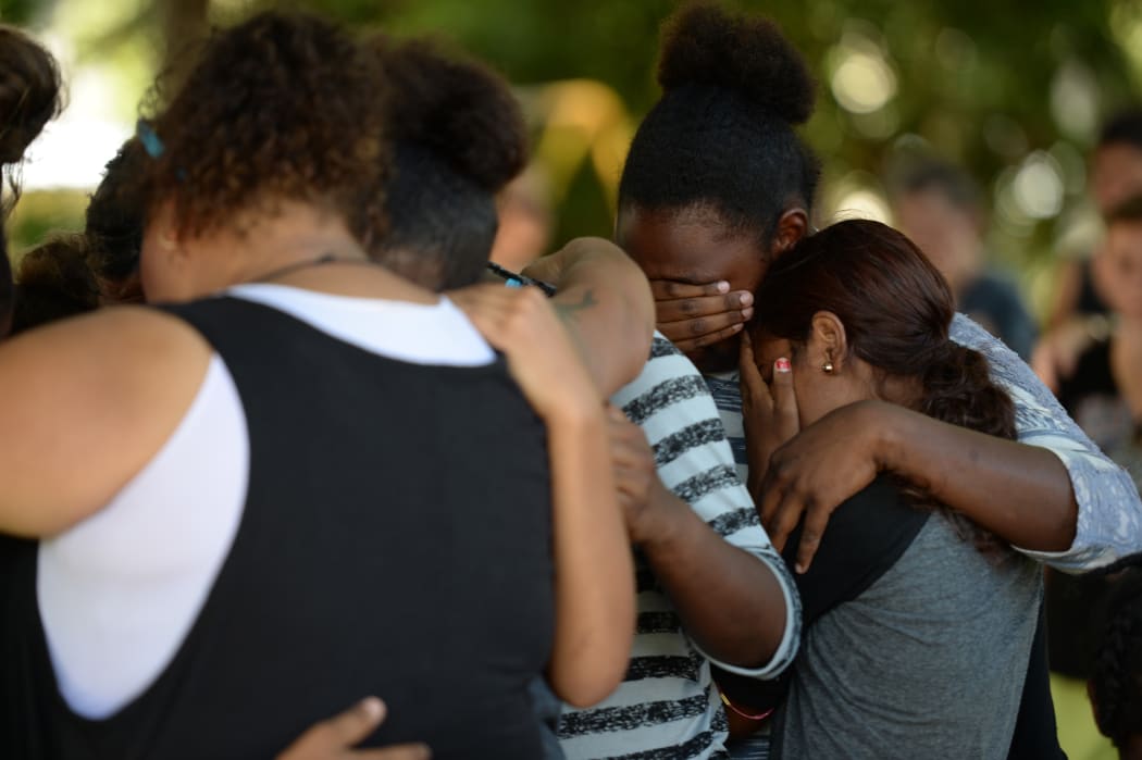 People comfort each other at the scene where the eight children were found.